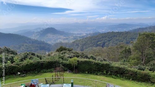 beautiful scenic view from dottabetta peak of green forest hill mountain with blue sky rain mist clouds background photo