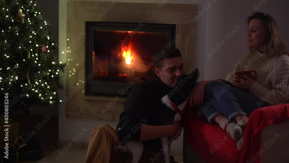 Christmas Eve at home during quarantine. A man and a woman are sitting near a fireplace in a room decorated for christmas Christmas Eve at home during quarantine. A man and a woman are sitting near a fireplace in a room decorated for christmas