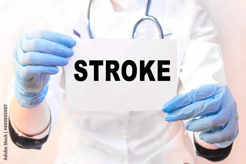The doctor's blue - gloved hands show the word STROKE - . a gloved hand on a white background. Medical concept. the medicine The doctor's blue - gloved hands show the word STROKE - . a gloved hand on a white background. Medical concept. the medicine