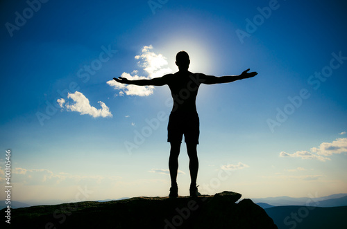 man stands on top of a mountain with open hand