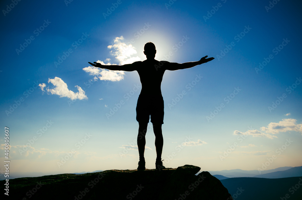 man stands on top of a mountain with open hand