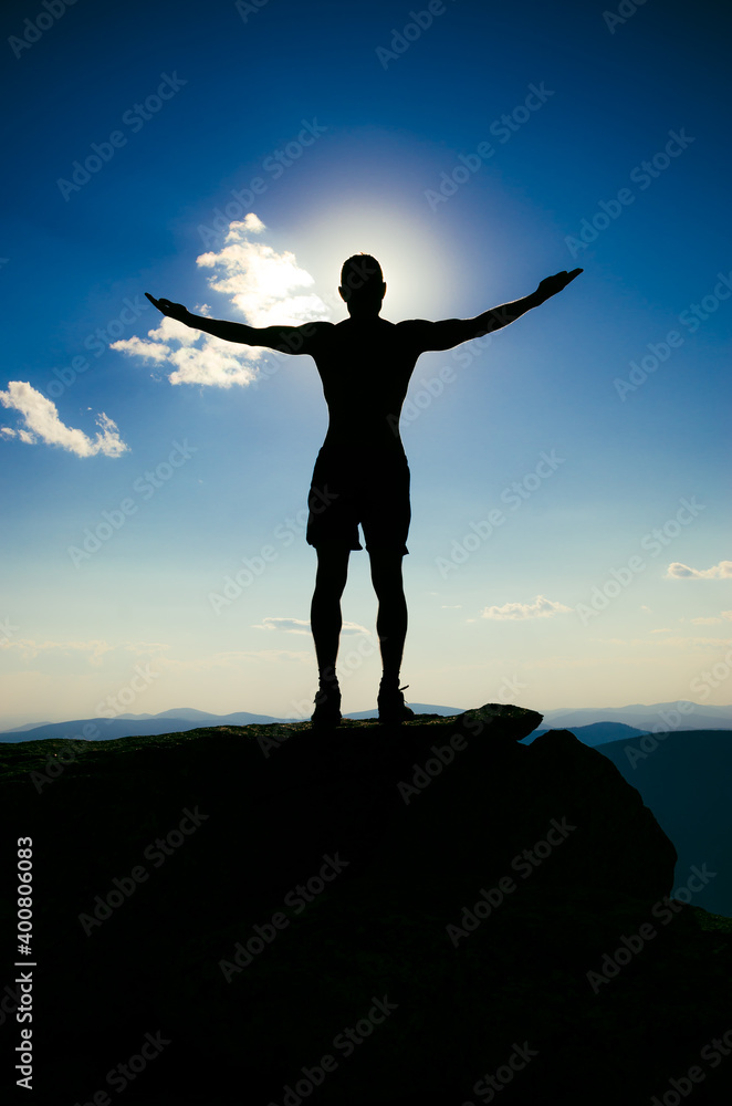 man stands on top of a mountain with open hand