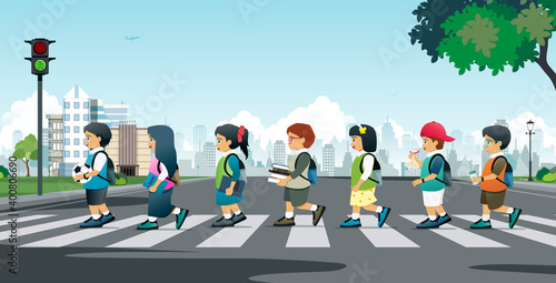 Students walking on a crosswalk with traffic lights.
