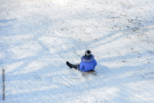 The girl is rolling down the hill which is covered with snow on a sled. photo