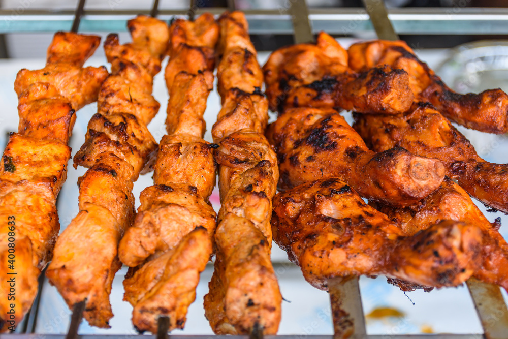 Closeup of skewed chicken legs tandoori slowly cooking over charcoal
