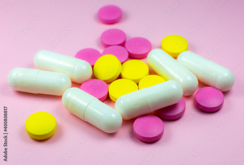 Colored pills and tablets on pink background. Close up. Medical treatment concept. Colored pills and tablets on pink background. Close up. Medical treatment concept.
