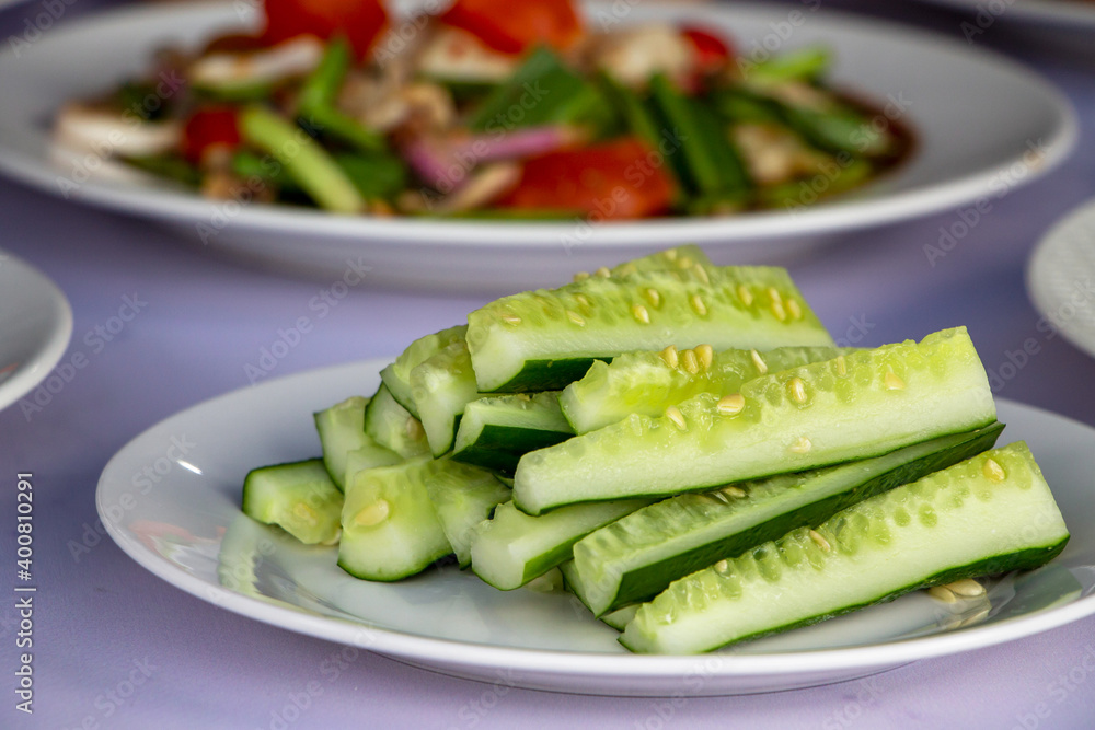 Fresh green cucumber slice on a white ceramic plate to eat with Thai spicy salad