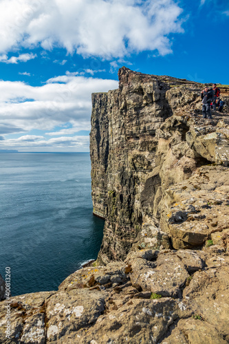Unrecognizable tourists taking photos on top of the steep coastline