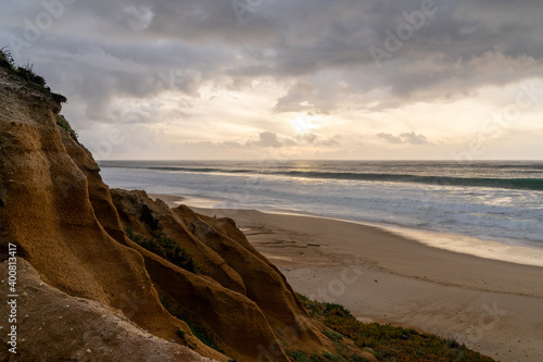 bizarre eroded sand dunes on the Atlantic Ocean with waves rolling in at sunset