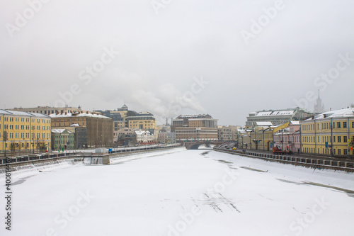 view of the Moskva river embankment with historic buildings and frozen water on a cloudy winter day in the old city center and space to copy in Moscow Russia