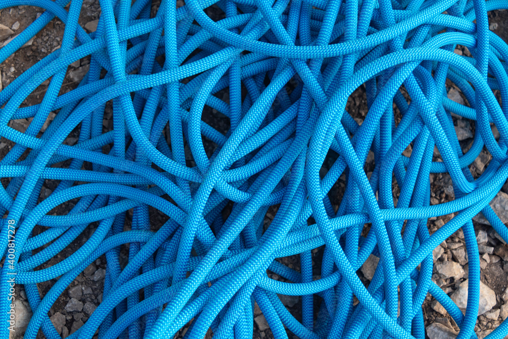 Blue rock climbing rope lying on the ground made of stones made a mess Blue rock climbing rope lying on the ground made of stones made a mess