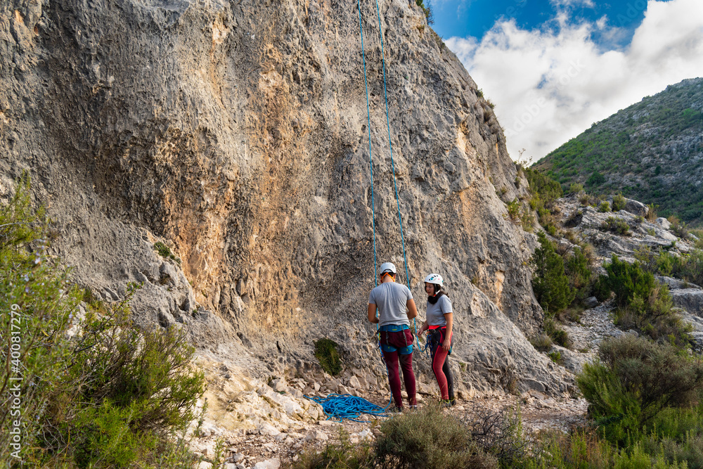 Healthy lifestyle climber couple preparing to start climbing next to a stone wall in nature