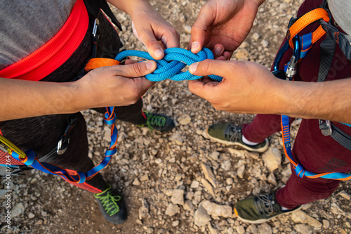 Hands of a couple of climbers making the eight knot in her harness to start climbing. Working as a team and in love