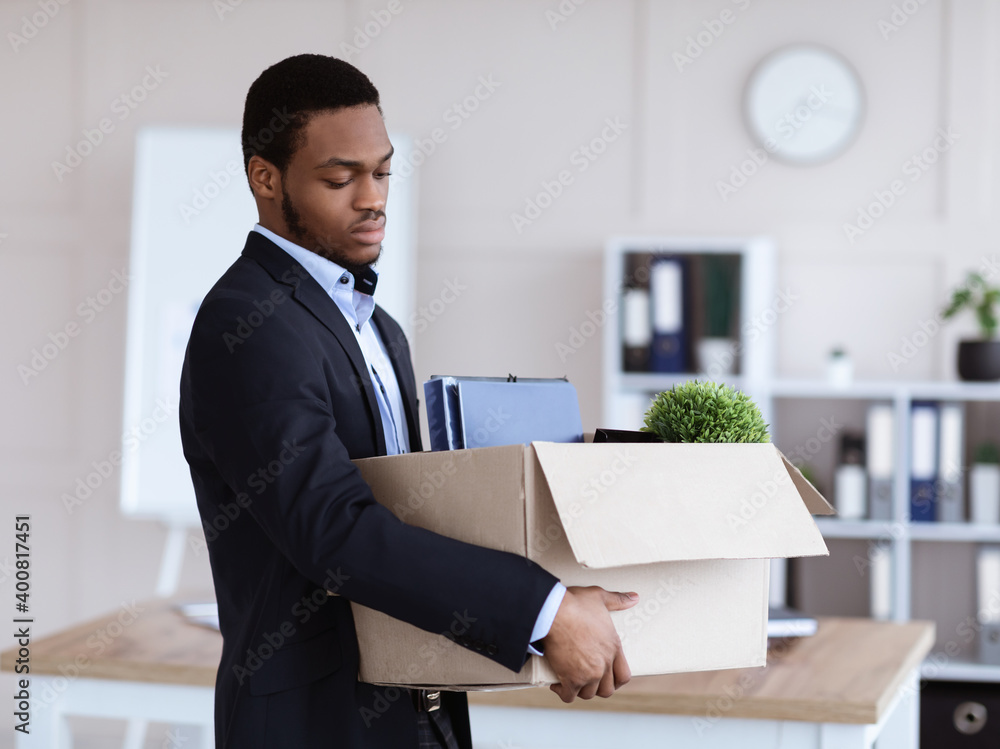 Upset black man got fired, holding box with his belongings Upset black man got fired, holding box with his belongings