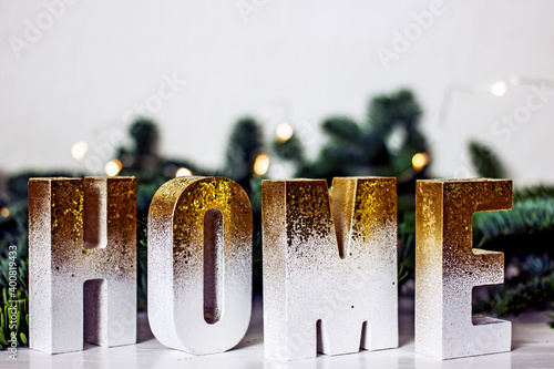 Home Sweet Home - Home lettering made of gold-plated wooden letters on the table next to a spruce branch. Home decor from handmade letters for christmas or winter holidays