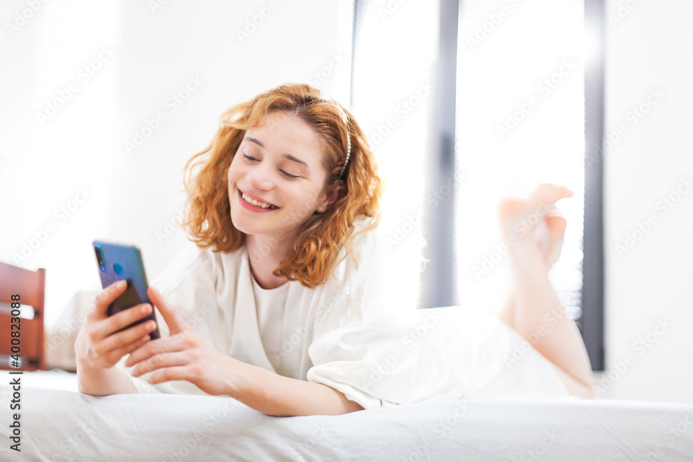 Casual careless girl at home using smart phone. Lying in bed scrolling social networks and taking selfy Casual careless girl at home using smart phone. Lying in bed scrolling social networks and taking selfy