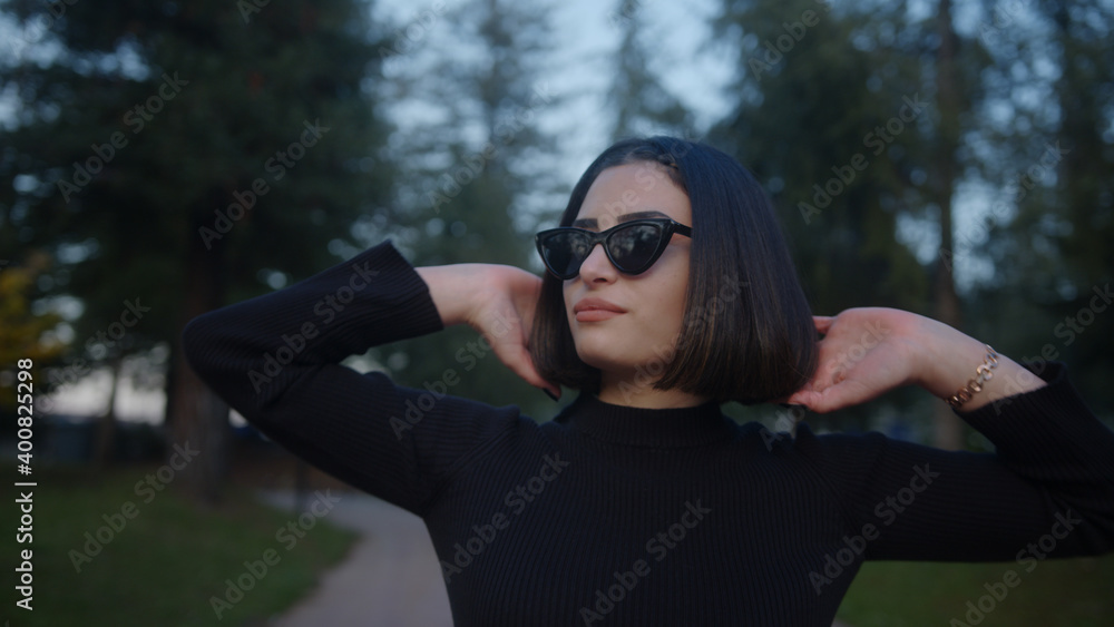 Short hair beautiful young woman walks down the street with sunglasses Short hair beautiful young woman walks down the street with sunglasses