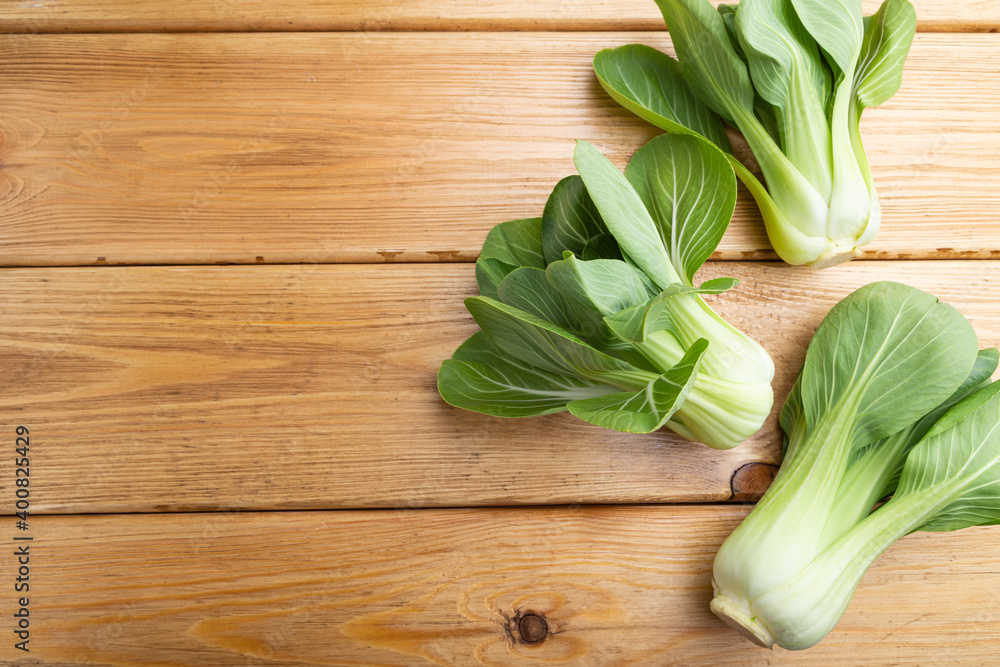 Fresh green bok choy or pac choi chinese cabbage on a brown wooden background. Top view, copy space. Fresh green bok choy or pac choi chinese cabbage on a brown wooden background. Top view, copy space.