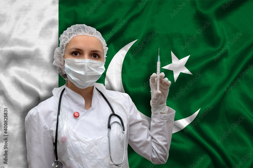 Young woman doctor in medical uniform on the background of the national flag of Pakistan is holding a syringe. The concept of a new vaccine against the disease, flu vaccine vaccination.