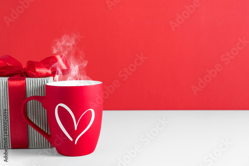 Valentine\'s day background, gift box, teaming cup coffee or hot tea on red background. Valentine day concept, design. Flat lay, top view, copy space