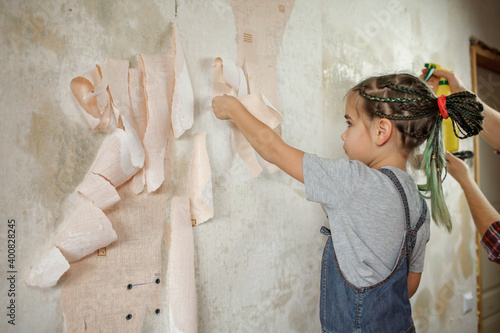 Father with kid repairing room together and unhanging wallpaper together
