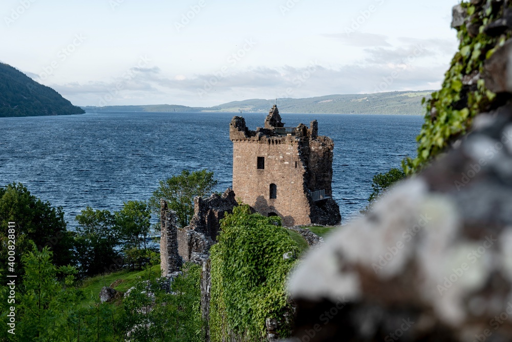 Urquhart Castle at nice sunset with near Drumnadrochit city in Scotland Highlands with blurred foreground