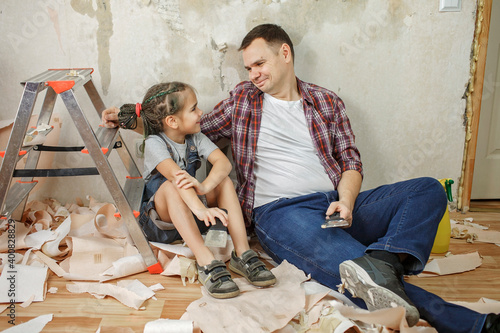 Fototapeta Father with kid repairing room together and unhanging wallpaper together
