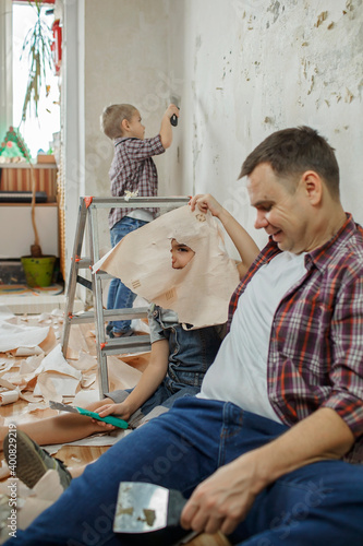 Father with kid repairing room together and unhanging wallpaper together photo