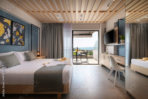 Side view of modern loft style bedroom with metal details, wooden furniture, abstract decor. Hotel apartment with sea view balcony, open air French window terrace