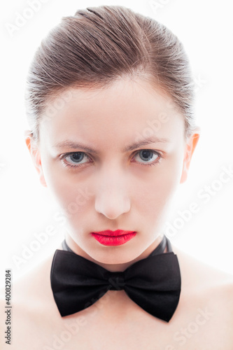 Serious woman with a black bow tie  red lipstick and hair tied back.