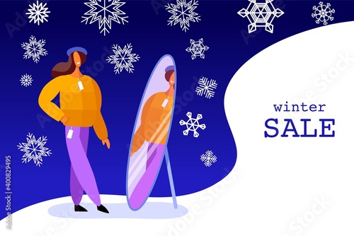 Woman tries on clothes. Winter shopping. A girl looks in the mirror. Winter background for sale