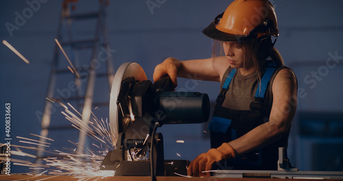 Female worker working with metal cutting saw