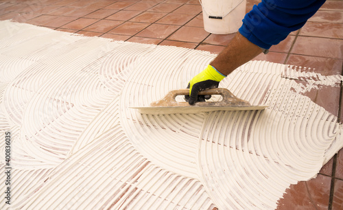 worker applying tile adhesive glue on the floor
 photo