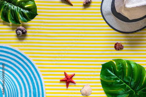 Summer composition. Tropical palm leaves, seashell, hats on yellow background. Creative summer composition on the yellow background. Top view.