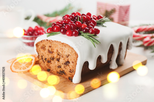 Traditional classic Christmas cake decorated with cranberries on wooden board. Bokeh effect