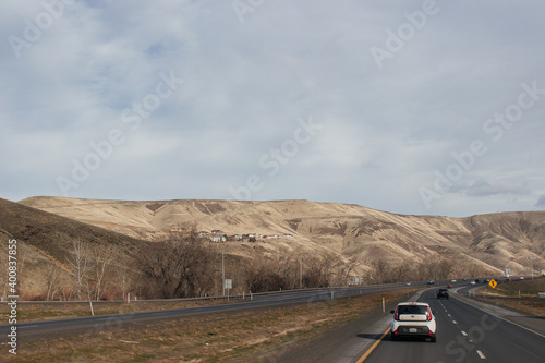 A beautiful landscape with a highway along which cars and trucks drive, on a sunny autumn day among the mountains, a blue sky with fluffy gray-blue clouds. Oregon, USA, 12-5-2019 © Liudmila