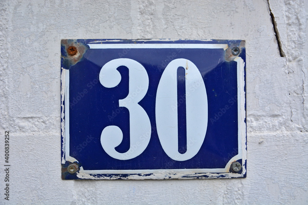 A blue house number plaque, showing the number thirty (30) A blue house number plaque, showing the number thirty (30)