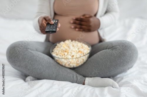 Cropped Shot Of Pregnant Woman With Popcorn And Remote Controller In Hands