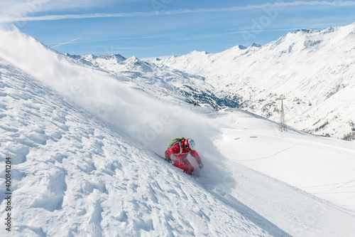 Stock picture of a freeride skier that is skiing fast downhill in deep powder snow. Big mountains and blue sky in the background. The location is Hochgurgl and Obergurgl in Austria