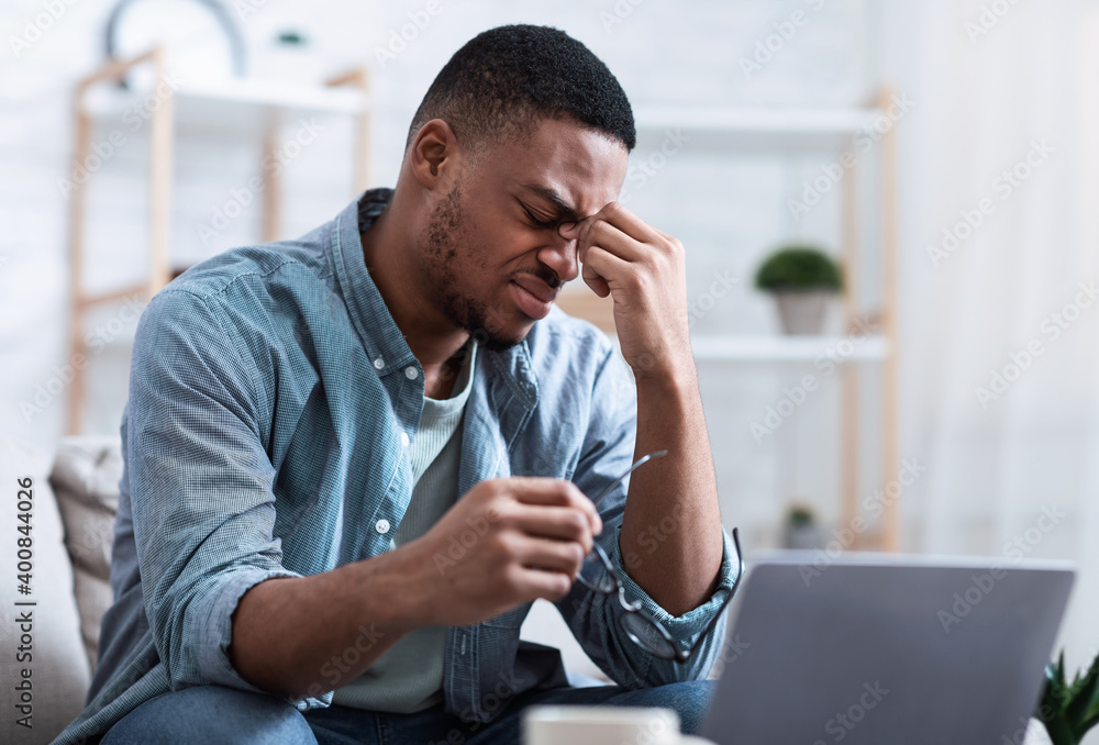African Man Massaging Nosebridge Tired After Work On Computer Indoors African Man Massaging Nosebridge Tired After Work On Computer Indoors