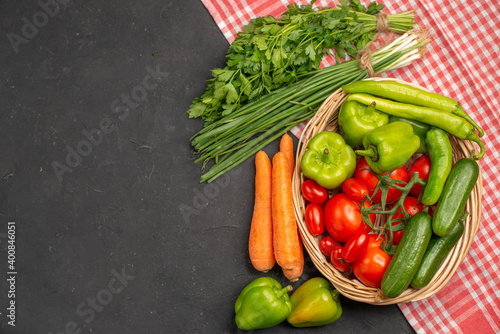 Above view of fresh various organic vegetables in a wooden basket on orange stripped towel on dark background