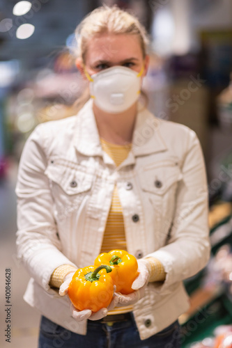 Teenage girl wearing protectice mask and gloves holding yellow bell peppers photo