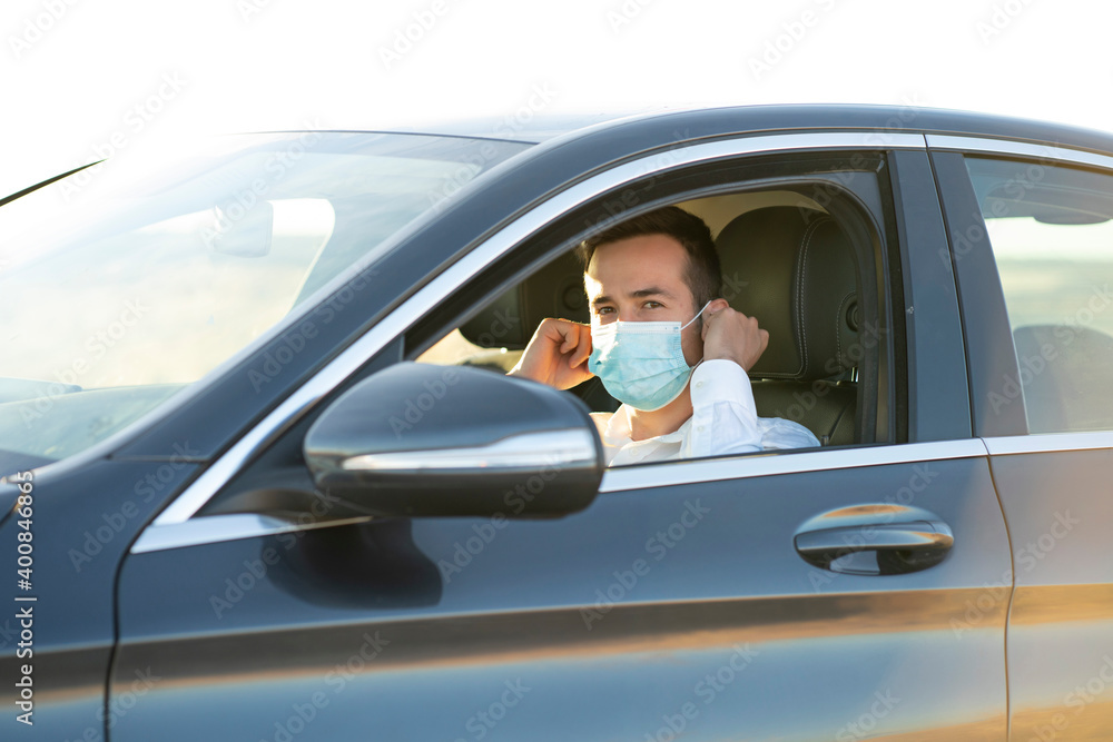 Young man wearing protective face mask while sitting in car during COVID-19 pandemic Young man wearing protective face mask while sitting in car during COVID-19 pandemic