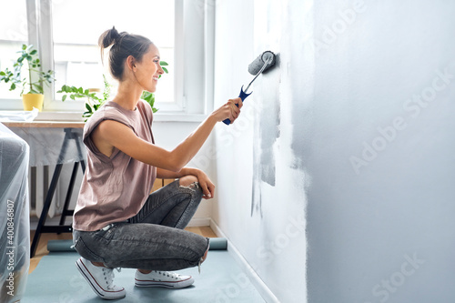 Woman smiling while painting wall at home