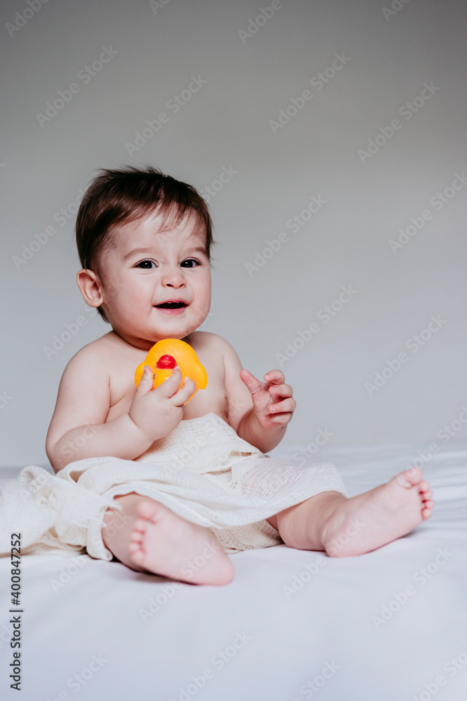 Cute boy playing with duck toy while sitting on bed at home Cute boy playing with duck toy while sitting on bed at home