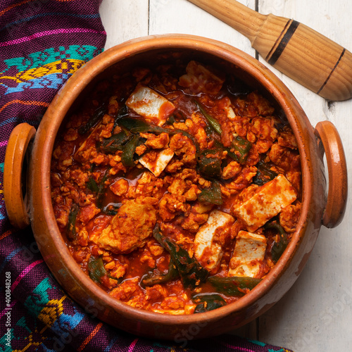 Mexican scrambled eggs in red sauce with poblano pepper and cheese on white background