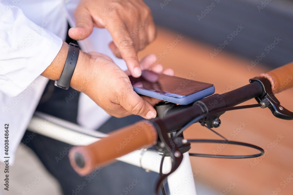 Close-up of man using smart phone while sitting on bicycle Close-up of man using smart phone while sitting on bicycle