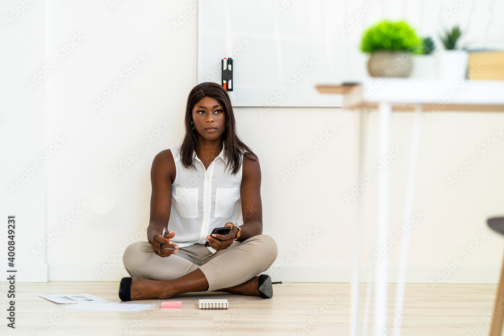 Businesswoman using mobile phone while sitting on floor at office Businesswoman using mobile phone while sitting on floor at office