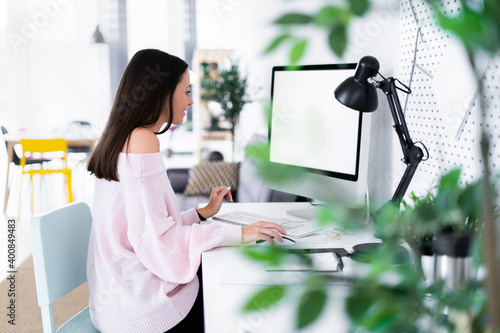 Young female blogger using computer at desk in loft apartment photo