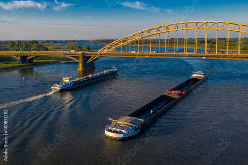 Netherlands, Gelderland, Nijmegen, Aerial view of barge and container ship sailing under bridge on river Waal